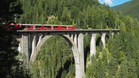 RhB-Zug fährt über eine hohe Steinbrücke