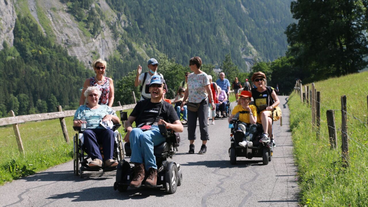 Wandergruppe mit Fussgängern und Rollstuhlfahrenden.