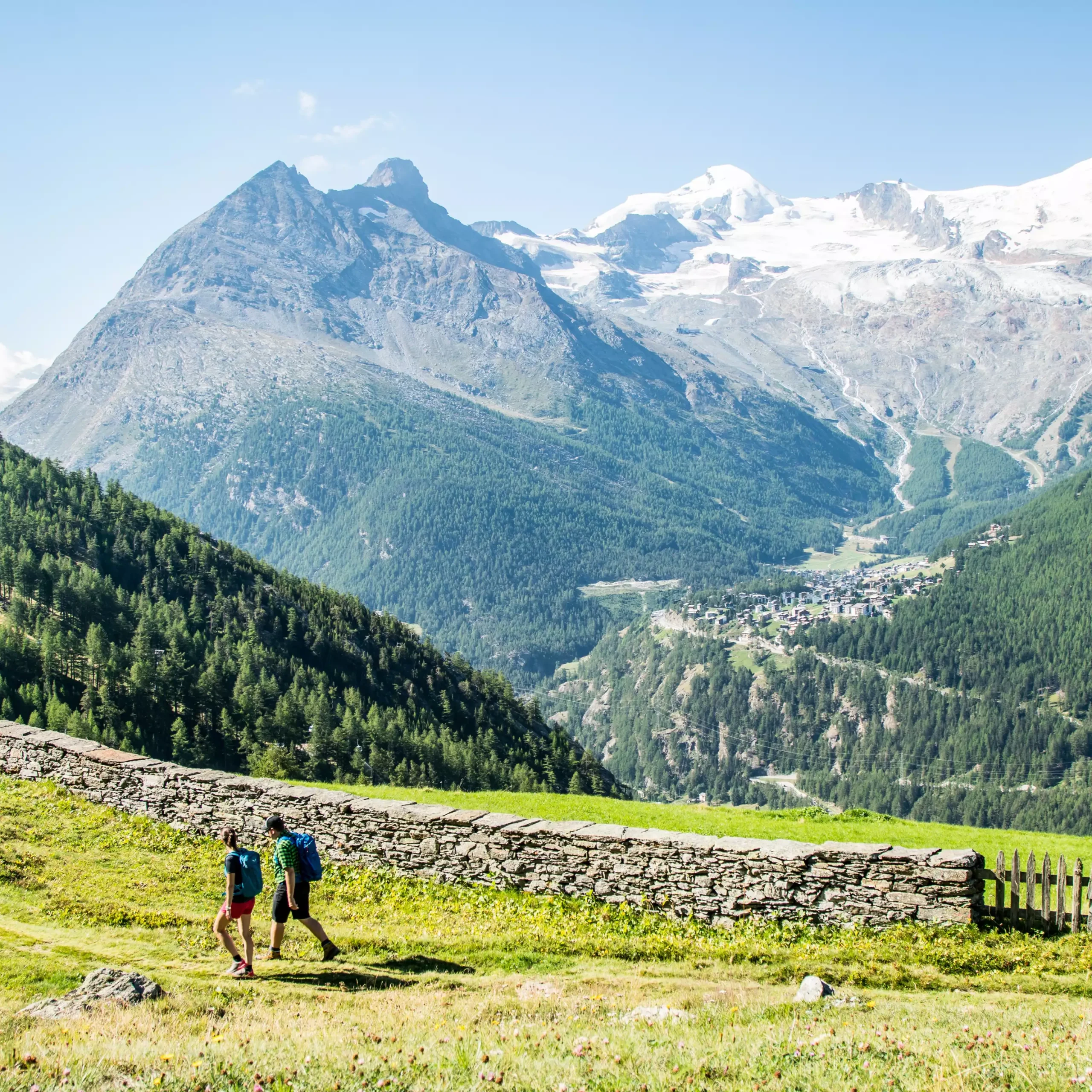 Zwei Wanderer in der Ferne vor einem imposanten Bergpanorama